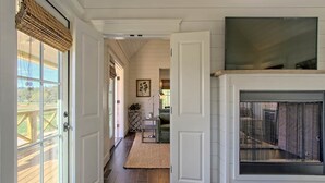 A hallway with a fireplace, a door leading to a room, and a window with a view of the outdoors. - Magnolia Cottage at Julep Farms (Dillard)