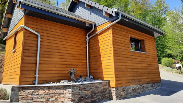 A wooden cabin with a stone foundation, a window, and a chimney.