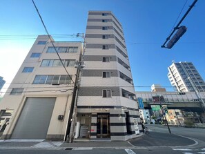 A multi-story building with a ground-floor entrance, a visible garage door, and a pedestrian crossing.