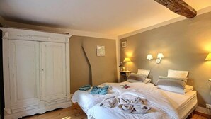 Een slaapkamer met een grote witte inbouwkast, twee bedden met handdoeken en wandlampen.