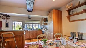 Een gezellige keuken met houten kastjes, een ontbijt klaar gezet tafel en een uitzicht op de aangrenzende eethoek.