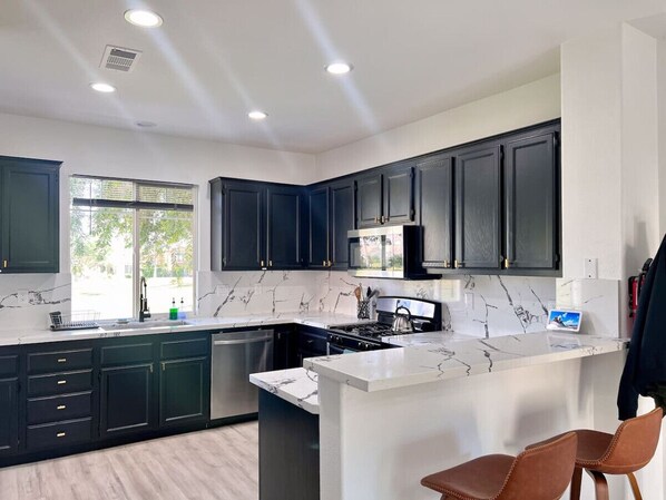 A modern kitchen with dark cabinets, a white marble countertop, and a central island.