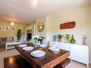 A dining area with a wooden table set for four, surrounded by white walls and a white cabinet.