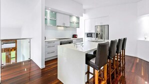 A modern kitchen with white cabinetry, a central island, and a bar area with stools.