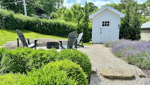 A well-maintained garden with a fire pit, outdoor seating, and a small shed.