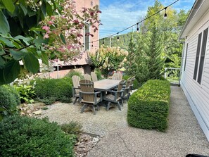 A patio with a table and chairs, surrounded by well-maintained hedges and a gravel path.