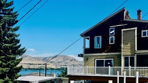 A two-story house with a balcony, a chimney, and a view of a lake and mountains. - Water Street Retreat (Chelan)