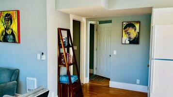 A hallway with a wooden floor, a bookshelf, and two paintings on the walls.