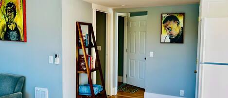 A hallway with a wooden floor, a bookshelf, and two paintings on the walls.