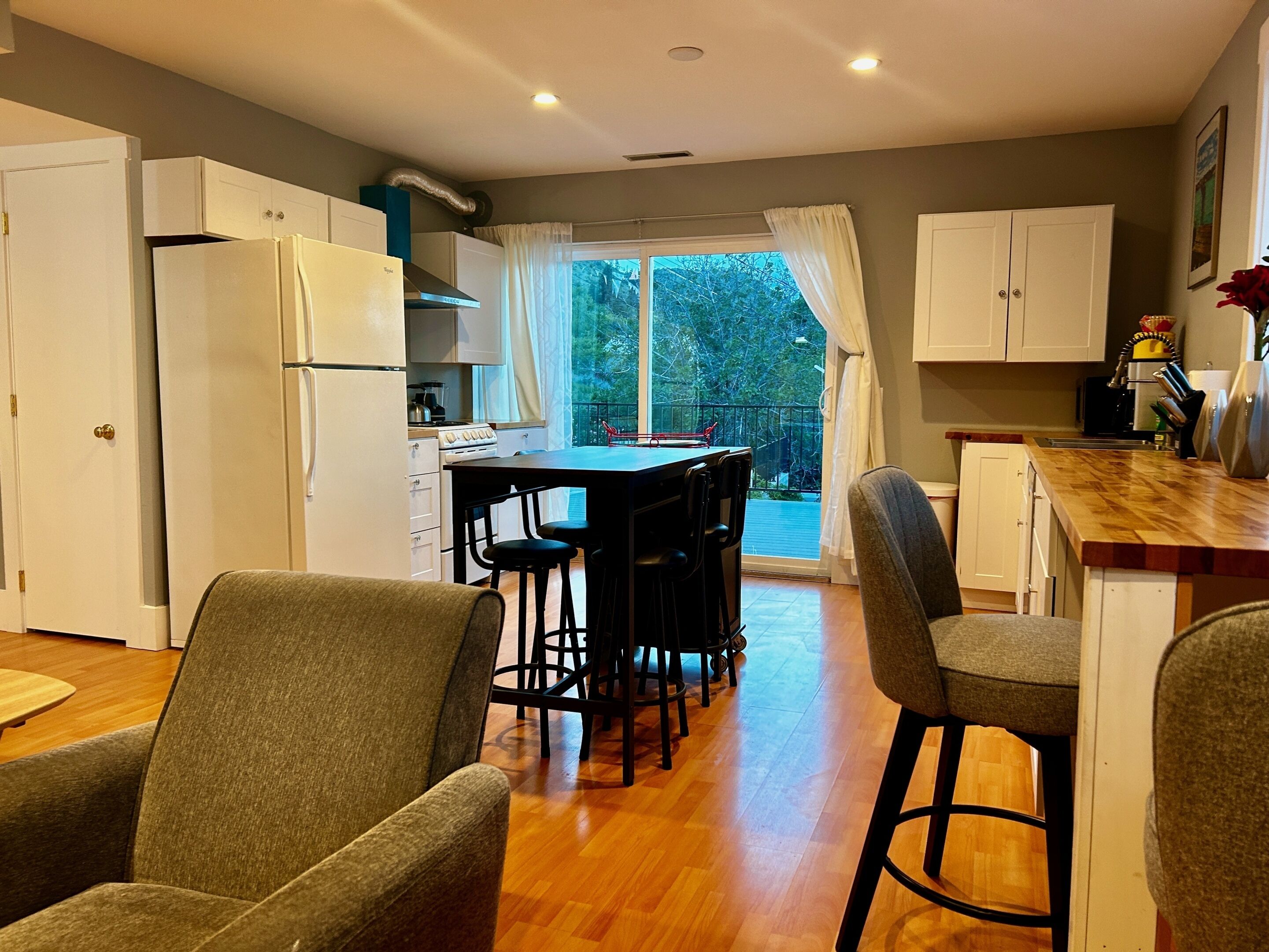 A kitchen with a dining area, wooden flooring, and a view of the outdoors.