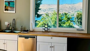 A kitchen with a large window overlooking a scenic landscape. - Water Street Retreat (Chelan)
