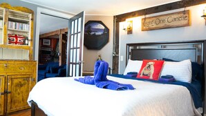 A bedroom with a bed, a wooden dresser, a bookshelf, and a wall-mounted sign.