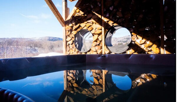 A hot tub with a wooden exterior and a clear view of the surrounding landscape.