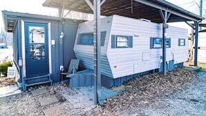 Ein Mobilheim mit überdachter Veranda und einem kleinen Anbau mit Tür.