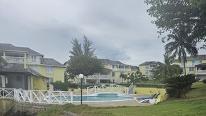 A coastal hotel with a swimming pool, a white bridge, and a rocky shoreline. - Apartment E6 (Tower Isle)