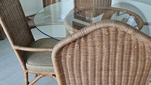 A dining area with wicker chairs and a glass table. - Apartment E6 (Tower Isle)