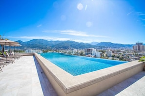 A swimming pool with a view of a city and mountains in the background. - Rooftop Views + Gym + Parking | 2BR in Versalles (Puerto Vallarta)