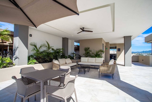 An outdoor patio with a dining table, chairs, sofas, and a ceiling fan.