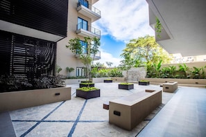 Une cour extérieure moderne, agrémentée de jardinières, d’un mur en pierre et d’un bâtiment doté de balcons.