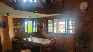 A dining area with a brick wall, a table with chairs, and a fan.