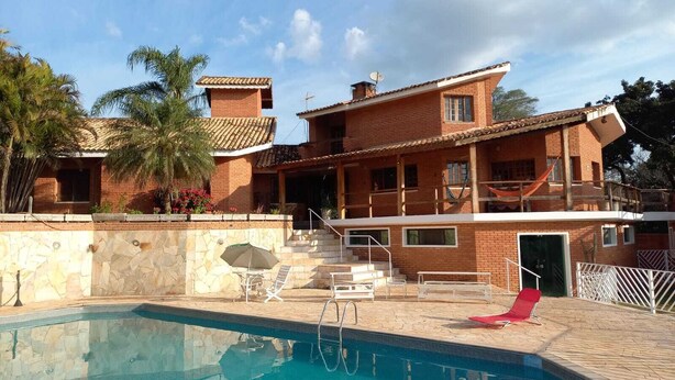 A two-story house with a swimming pool, a covered patio, and a brick exterior.