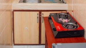 Une cuisine de taille réduite, avec des meubles de rangement en bois, un évier et une cuisinière à gaz rouge.