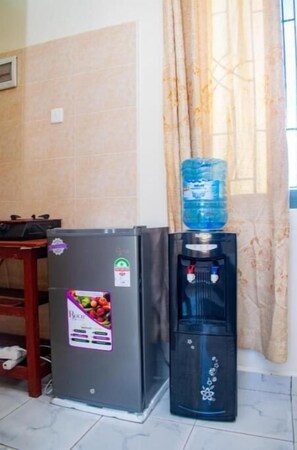 Kitchenette with refrigerator, water dispenser, and table.