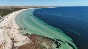 An aerial view of a beach with clear turquoise waters, a sandy shoreline, and sparse vegetation. - Coastal Break - Family Escape in Port Hughes (Port Hughes)