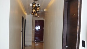 A hallway with a polished floor, a ceiling light fixture, and a door at the end. - FERN INN Kolkata (Kolkata)