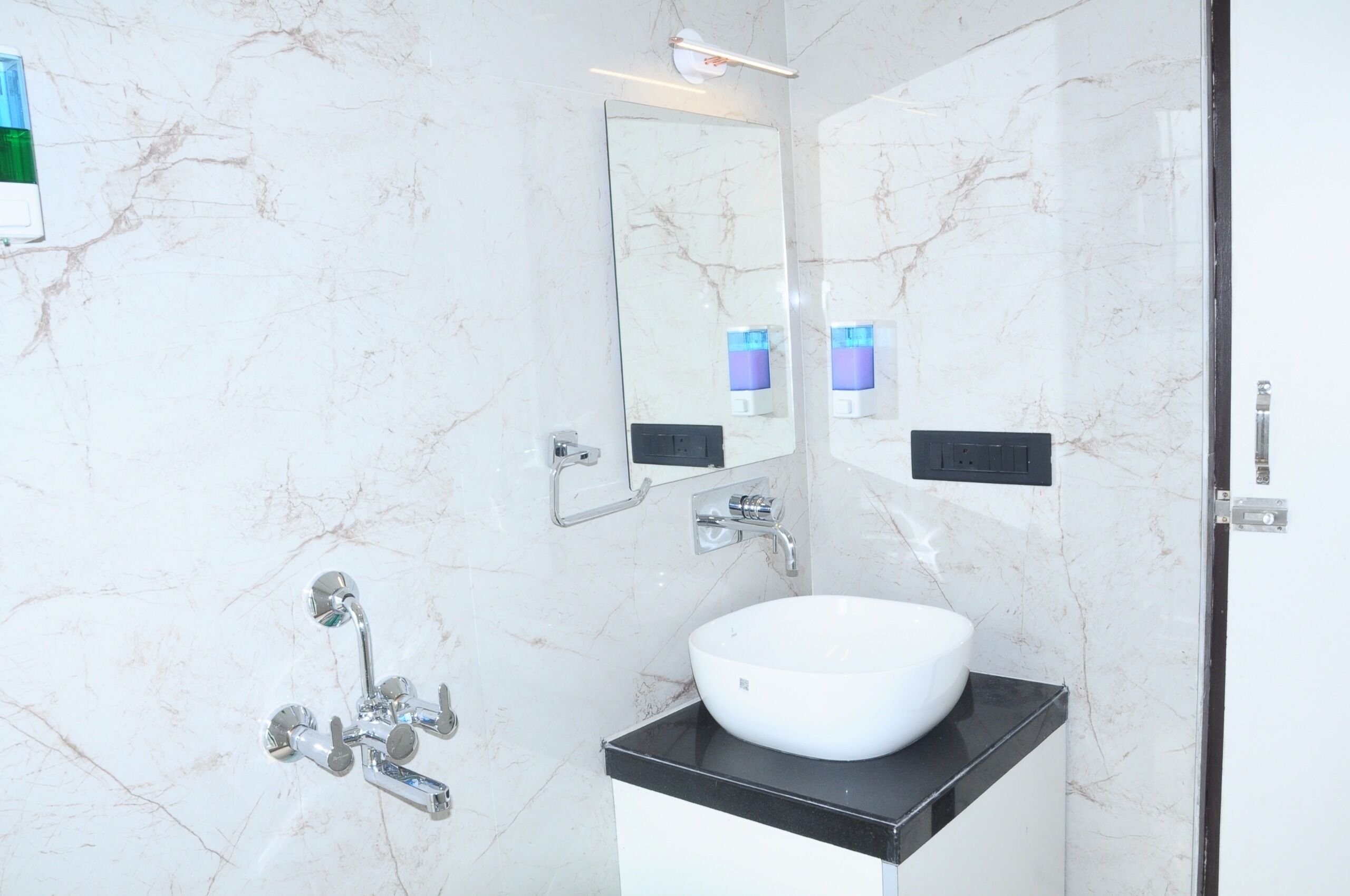 A modern bathroom with a white marble sink, a large mirror, and a handheld showerhead.