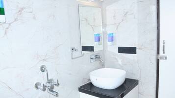 A modern bathroom with a white marble sink, a large mirror, and a handheld showerhead.
