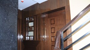 A wooden staircase with a metal handrail, leading to a landing with a glass door. - FERN INN Kolkata (Kolkata)
