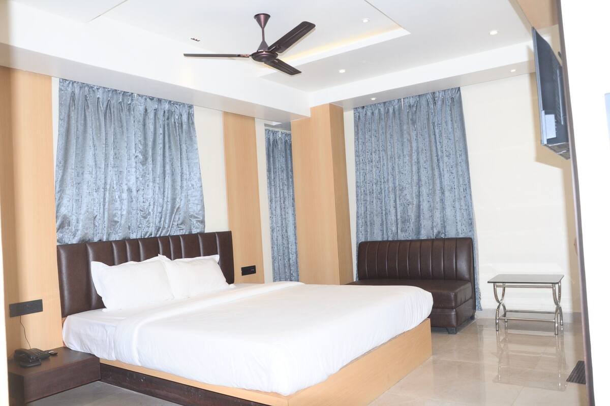 Une chambre d’hôtel moderne avec un grand lit, un ventilateur de plafond et une petite table.