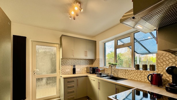 A modern kitchen with a large window, a built-in oven, and a sink. - Sandringham House Serene Escape Cottage (Cleethorpes)