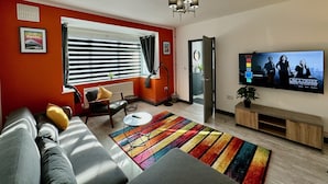 A modern living room with a sofa, a coffee table, a TV, and a colorful striped rug. - Sandringham House Serene Escape Cottage (Cleethorpes)