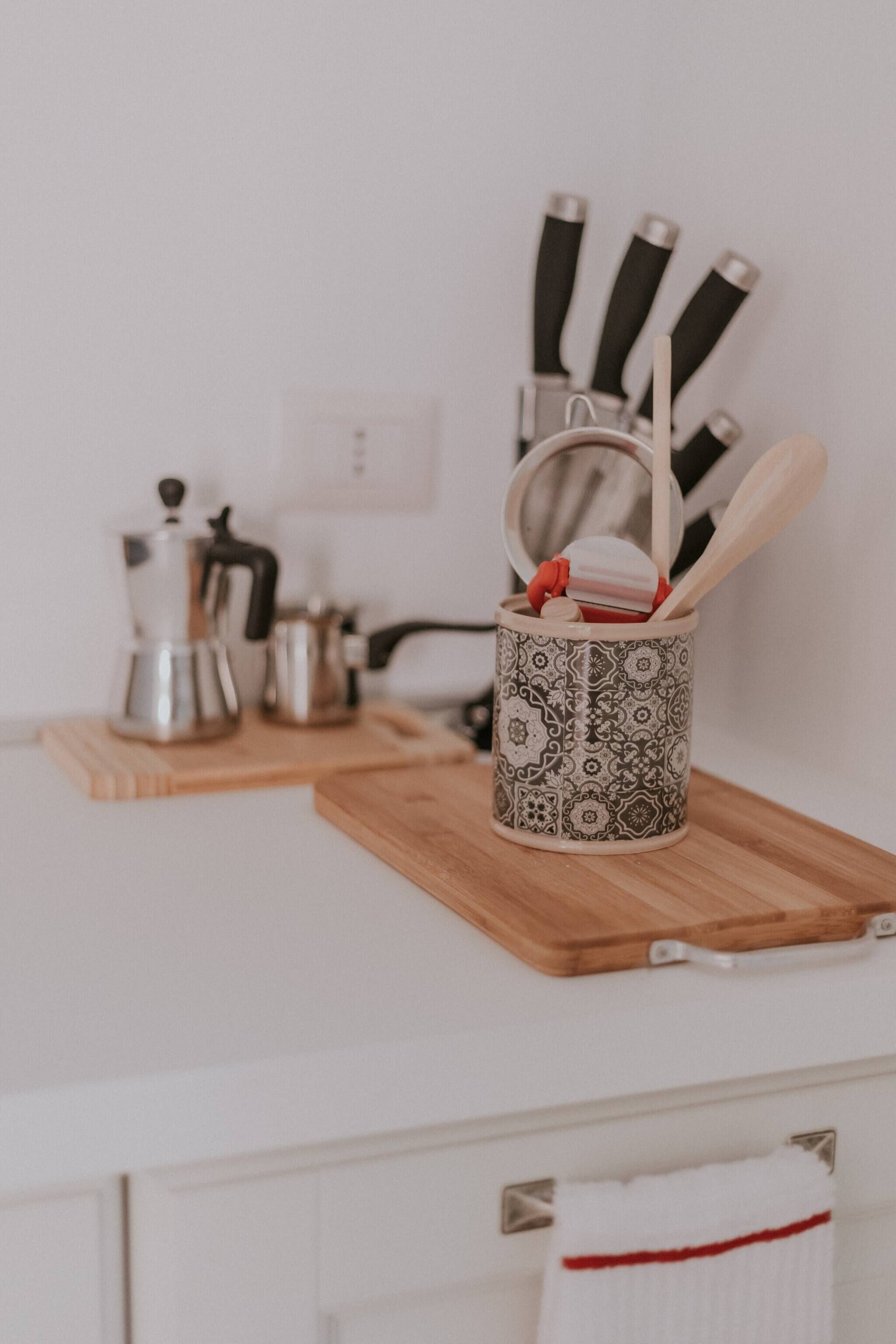 Eine Küche mit Kaffeemaschine, Wasserkocher und einem Besteckhalter auf einer Holzbrett.