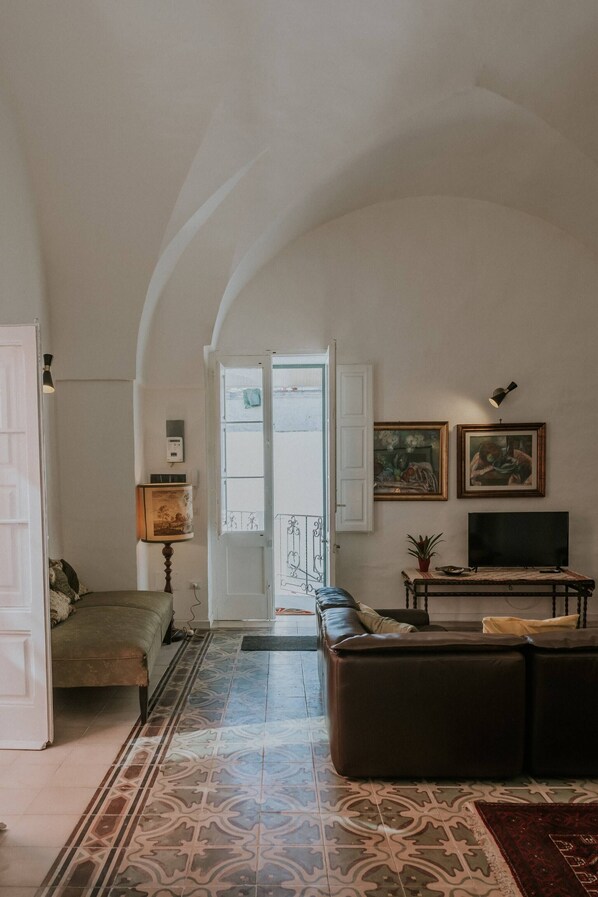 A living room with a sofa, a television, and a patterned floor.