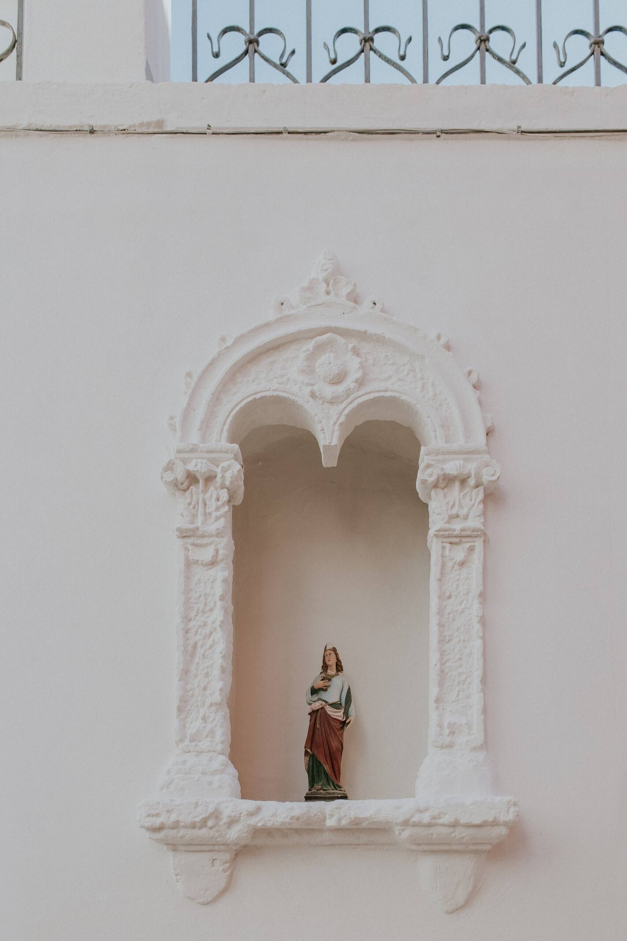 A white architectural detail with a statue of a figure in a niche.