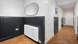 Un couloir avec des lambris noirs et blancs, un radiateur blanc et une porte dotée d’un cadre blanc.