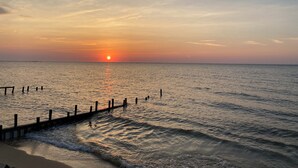 Un atardecer sobre un mar tranquilo con un muelle de madera que se adentra en el agua.