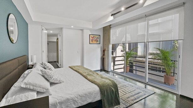 A modern bedroom with a large bed, a view of the balcony, and a potted plant. - 113-B201 Luxury 3br/2.5 baths in Condesa (Mexico City)