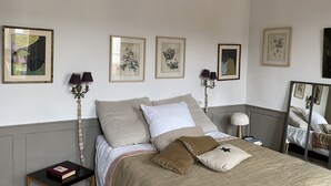 Un dormitorio ordenado con cama, mesitas de noche y lámparas de pared.