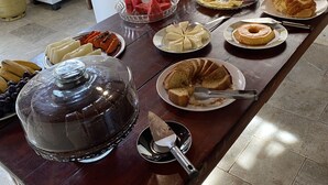 A buffet table with various food items and a refrigerator in the background. - Pousada Sunflower (Pirenópolis)
