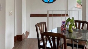 Un comedor con una mesa de vidrio, sillas de madera y un farol colgante.