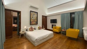 Una habitación de hotel moderna con una cama grande, un televisor de pantalla plana, un sillón amarillo y una pequeña mesa.