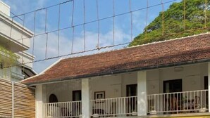 Un edificio de dos pisos con piscina, mobiliario exterior y plantas en macetas.