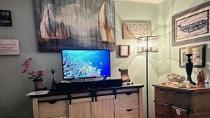 A room with a wooden cabinet, a flat-screen TV, and various wall decorations including a sign that says "HOPE Anchors the Soul". - Sandy Point Shalom - Ocean access and sunrise view - 20 mins to Bellingham (Ferndale)