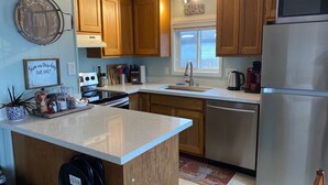 A kitchen with wooden cabinets, a stainless steel refrigerator, a sink, and a stove. - Sandy Point Shalom - Ocean access and sunrise view - 20 mins to Bellingham (Ferndale)