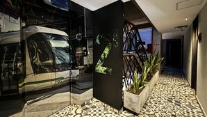 Un intérieur moderne agrémenté d’une décoration murale en forme de bus, d’un sol à motifs géométriques et d’un escalier avec une rampe en métal.