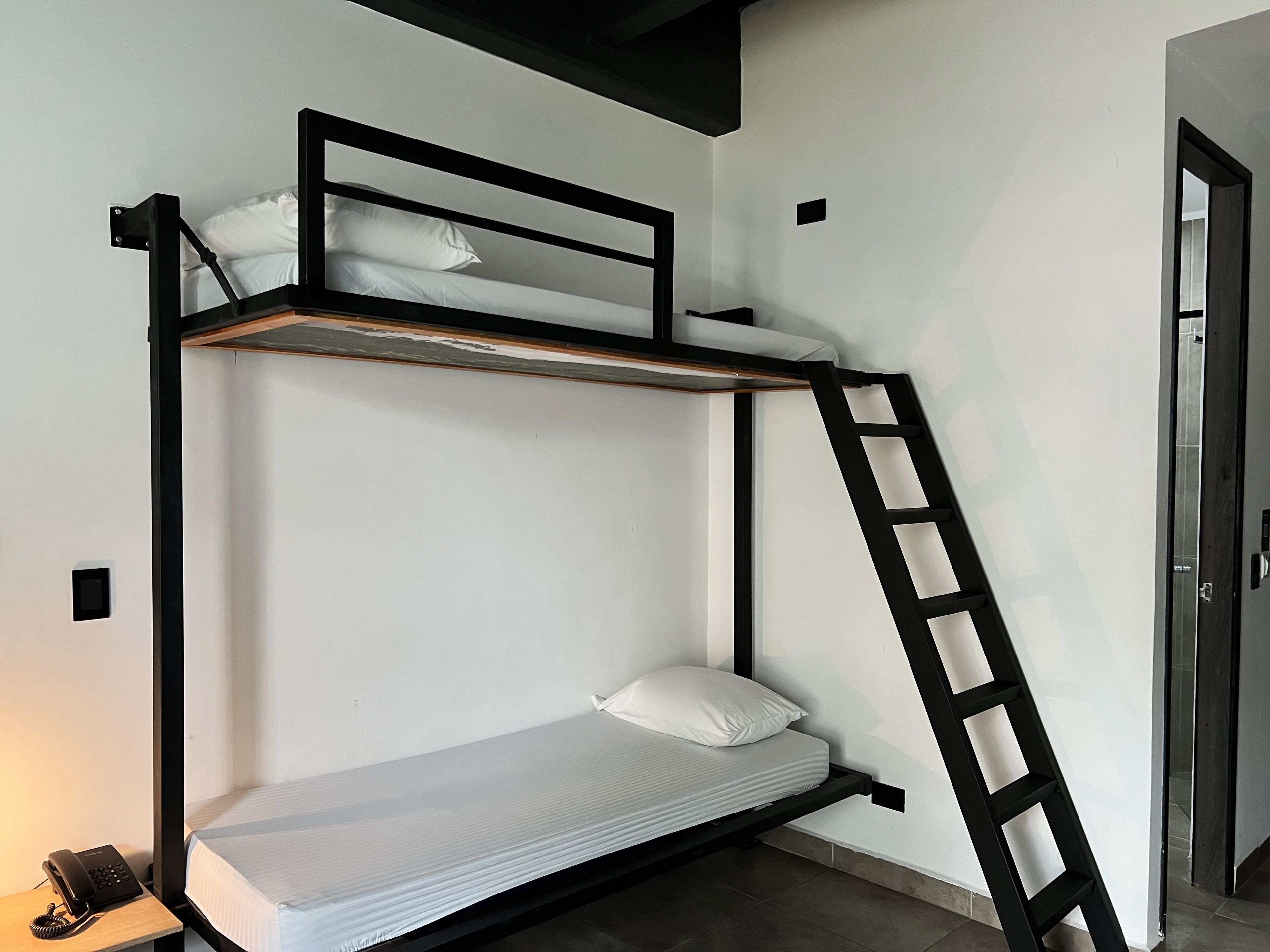 Ein Stockbett mit einer Stehle, einem Nachttischtelefon und einem kleinen Tisch.